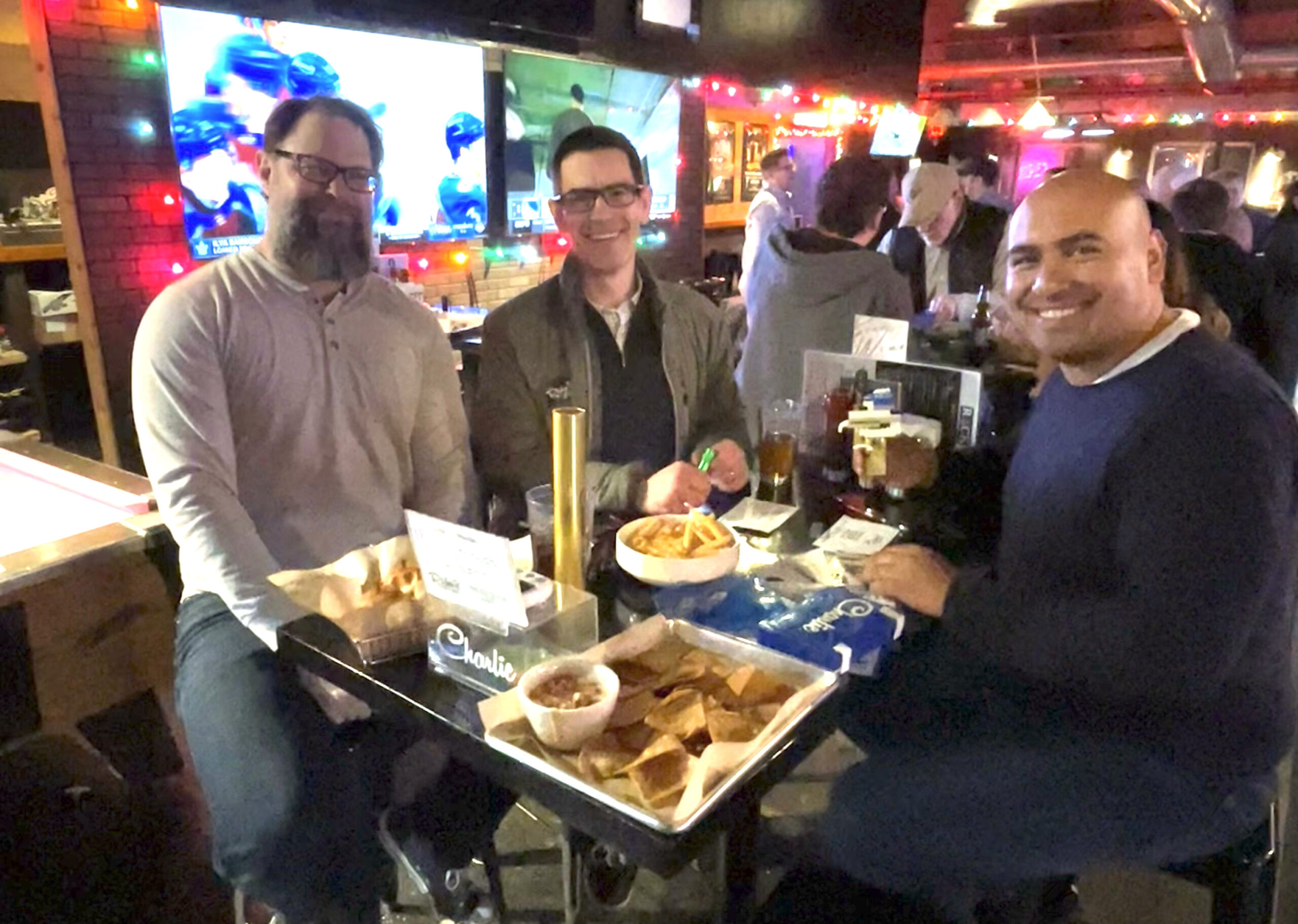 THREE MEN EATING FOOD IN A BAR<br />
