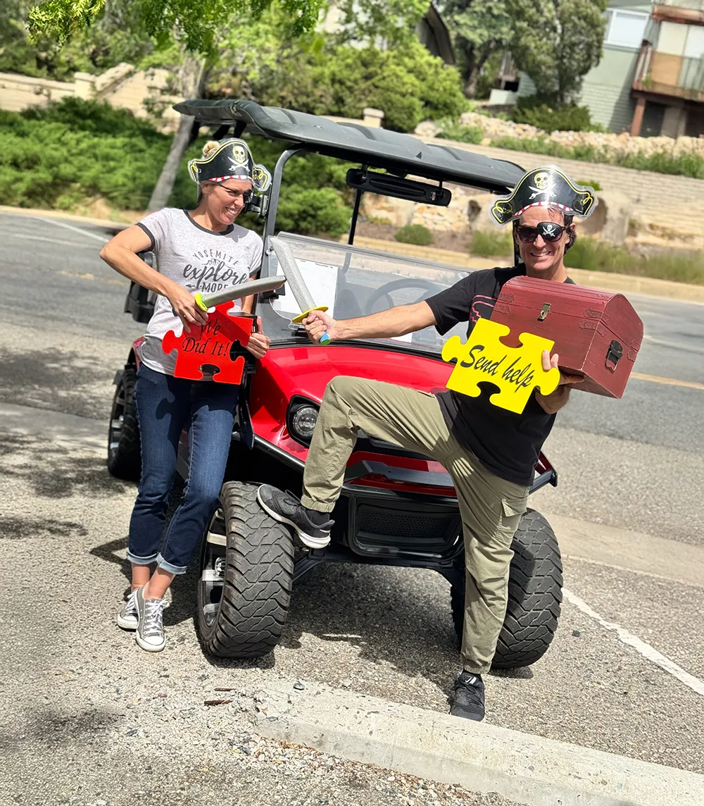 Couple in pirate costumes posing on Puzzle Rides golf cart during Pirate’s Treasure Adventure tour in Prescott